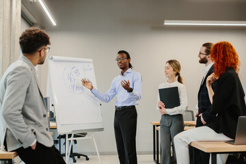 Businessman explaining strategy on whiteboard to colleagues in office meeting