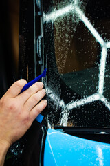 Micro squeegee to press blue vinyl wrap deep into tight vehicle trim gaps. Micro squeegee tool...