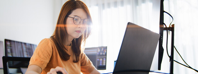 Asian female freelance programming developer work alone using desktop and laptop computer at home office. Information technology, smart woman, software engineer programmer coding job. Copy space