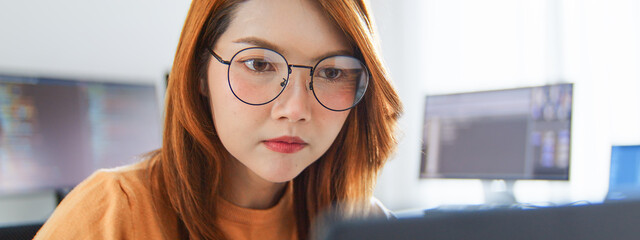 Asian female freelance programming developer work alone using desktop and laptop computer at home office. Information technology, smart woman, software engineer programmer coding job. Copy space