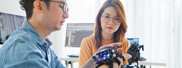 Asian male, female programming developer work together at home office, coding robotic arm machine. Information technology, software engineer programmer job, man woman coworker teamwork concept