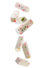 Sticks of marshmallow with colorful pieces of candied fruits are falling in space. Isolated on white
