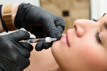 Beautician injecting lip filler into patient's lips for augmentation