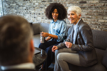 Two diverse colleagues on coffee break chatting with male colleague