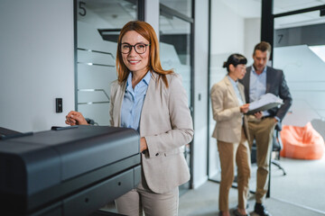 caucasian businesswoman use photocopy machine in hallway of company