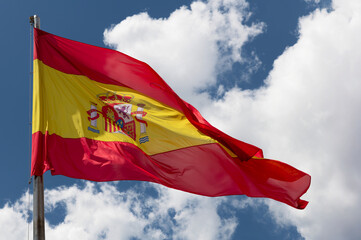 Spanish National Flag Waving Against Blue Sky with Clouds.