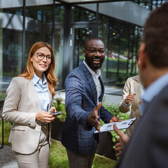 Black and caucasian man handshake agreement in front of company