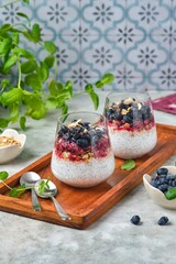 Chia pudding with nut granola, honeysuckle berry puree and whole honeysuckle  berries in...