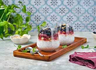 Chia pudding with nut granola, honeysuckle berry puree and whole honeysuckle  berries in...