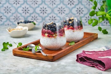 Chia pudding with nut granola, honeysuckle berry puree and whole honeysuckle  berries in...