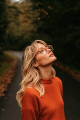 Naklejka premium Young Girl Gazes Upward on a Forest Path During Autumn in a Cozy Sweater.
