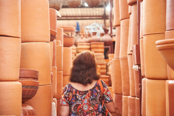 Unknown person walking in an aisle formed by stacks of ceramic pots in a store in Raquira, Boyaca, Colombia, a tourist town known for its craftsmanship and its pottery.