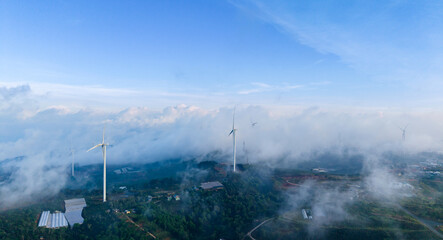 Fototapeta premium Turbines for renewable electric power production. Drone view Wind generators with fog and clouds in mountains, panorama industry landscape