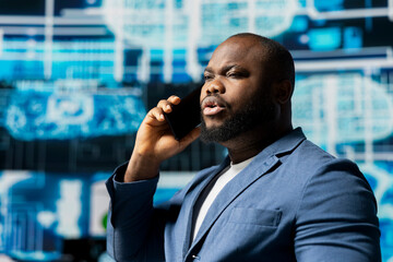 Black tech specialist talking on a smartphone call in an AI powered environment, representing...