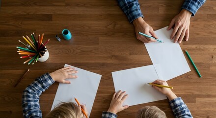 Vista superior de pai e filho desenhando com l&aacute;pis de cor sobre mesa de madeira &ndash; momento de conex&atilde;o familiar