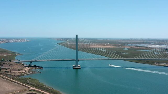 Cars and boats are crossing the international bridge over the guadiana river, connecting ayamonte, spain, and castro marim, portugal, on a sunny day