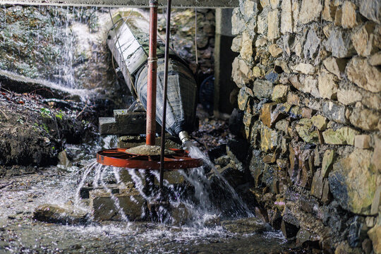 Watermill mechanism in operation with flowing water and stone structure at an old mill site