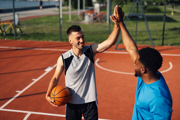 Two basketball players giving high five after successful play on court