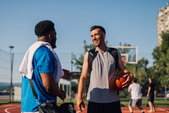 Two basketball players talking and smiling on outdoor court