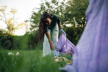 Young woman picking up trash in a park