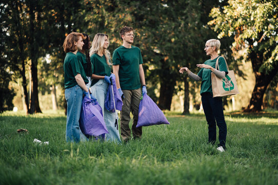 Group of volunteers collecting garbage together in park - Powered by Adobe