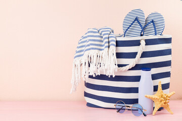 Blue beach bag with summer accessories on wooden table