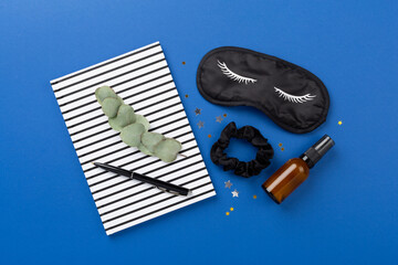 Sleeping mask with accessories on color background, top view. Sleeping routine concept