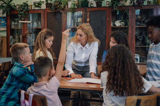 Elementary school students raising hand in classroom during lesson