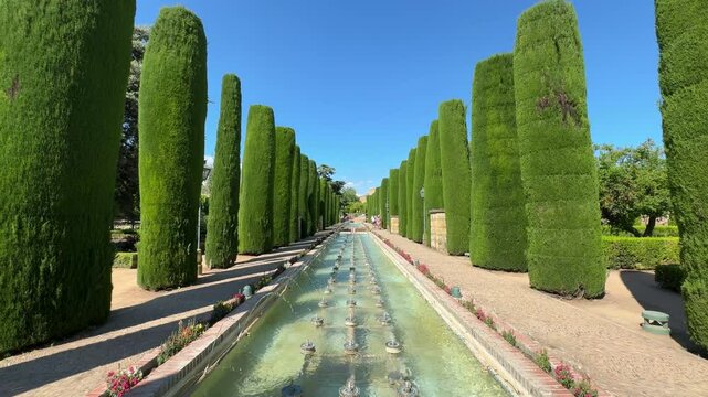 Cordoba, Spain - Alcazar gardens in Cordoba, Spain, Jardines del Alcazar de los Reyes Cristianos, water fountain with statue of king and queen and Christopher Columbus