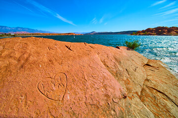 Red Rock Heart Carving by Desert Lake with Blue Water Low Eye Level Perspective