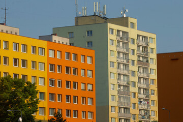 A striking yellow and orange building featuring antennas prominently placed on its rooftop, adding...