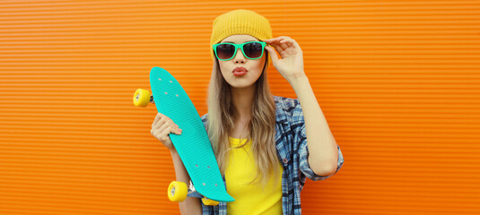 Stylish young woman with skateboard in hat, happy modern teenage girl posing on orange wall © rohappy