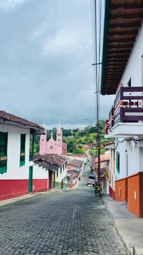 Traditional colonial street leading to pink church in Jerico, Colombia