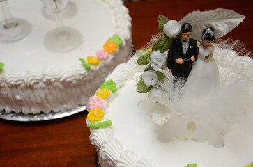 Elegant wedding cake with floral decor and couple topper on wooden table