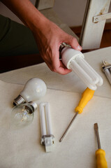 Person exploring energy-efficient lighting with bulbs and tools on table