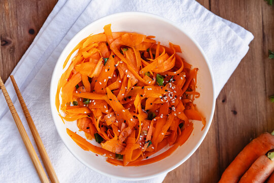 Ribbon carrot salad with green onions and sesame seeds served in a bowl