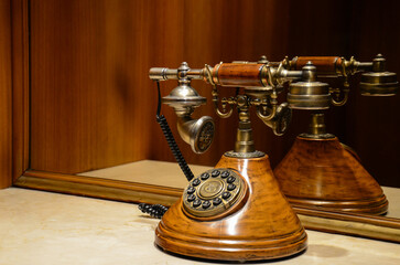 Vintage rotary dial phone with wooden base on glossy surface reflection