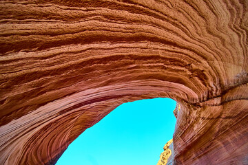 Sandstone Arch and Striated Rock Layers Framing Blue Sky Low Angle View