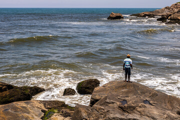 Itanhaem, Sao Paulo, Brazil. January 22, 2018 A fisherman on rocky coast, fishing and gazing at the...