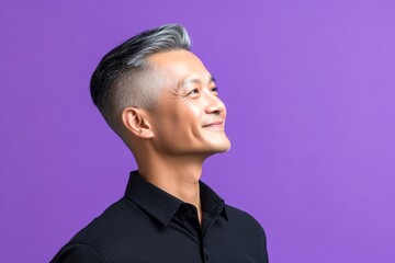 Fototapeta premium Trendy men's disconnected undercut haircut - midlife southeast asian man with short hair. A midlife man posing for a portrait. Purple solid background. Conceptual art of style for aging men.
