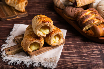 Creamy custard-filled puff pastries displayed on a rustic wooden board.