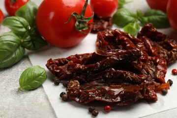 Delicious sun dried tomatoes, fresh vegetables and spices on gray textured table, closeup