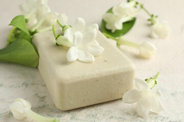 Bar of soap and jasmine flowers on light table, closeup