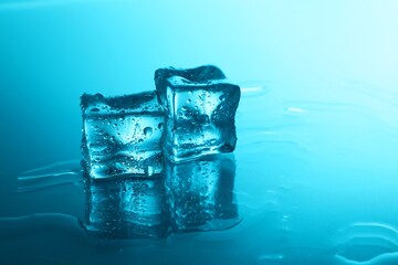 Cubes of clear ice on light blue background, space for text