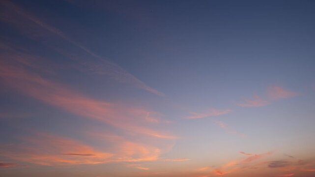 A sunset timelapse with warm orange hues blending into soft purple and pink tones. Rays of light stretch through the sky, highlighting wispy clouds and creating a peaceful, radiant close to the day.
