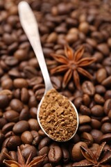 Spoon with granulated instant coffee and star anise on beans, closeup