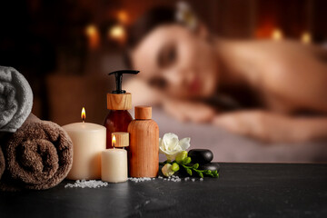 Spa therapy. Woman lying on massage table and composition with body care products in salon, selective focus