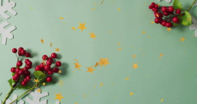 Fototapeta Featuring red berry sprigs on mint table, scattering snowflakes and gold star confetti, copy space