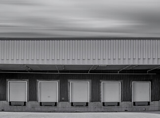 Obraz premium Desaturated image of closed loading dock, doors, blurred clouds, nobody