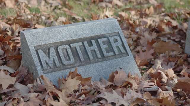 Fall leaves on mother headstone at graveyard 4k
